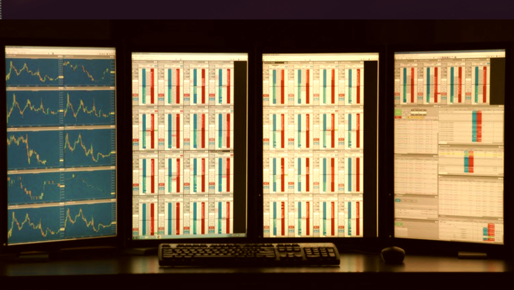 Trading workstation with multiple market data screens showing charts and order books.