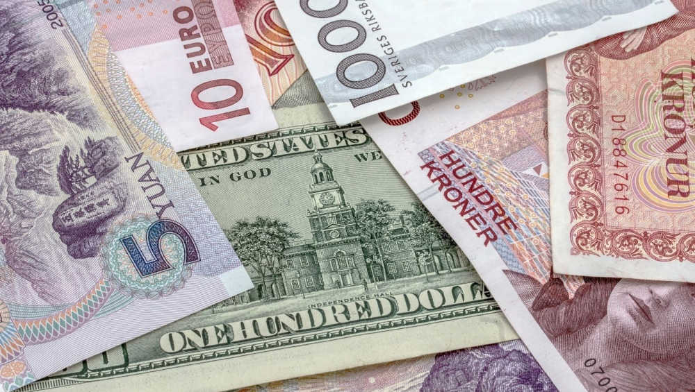 Close-up pile of international banknotes, including the US Dollar, Chinese Yuan, Euro, and Scandinavian Kroner.