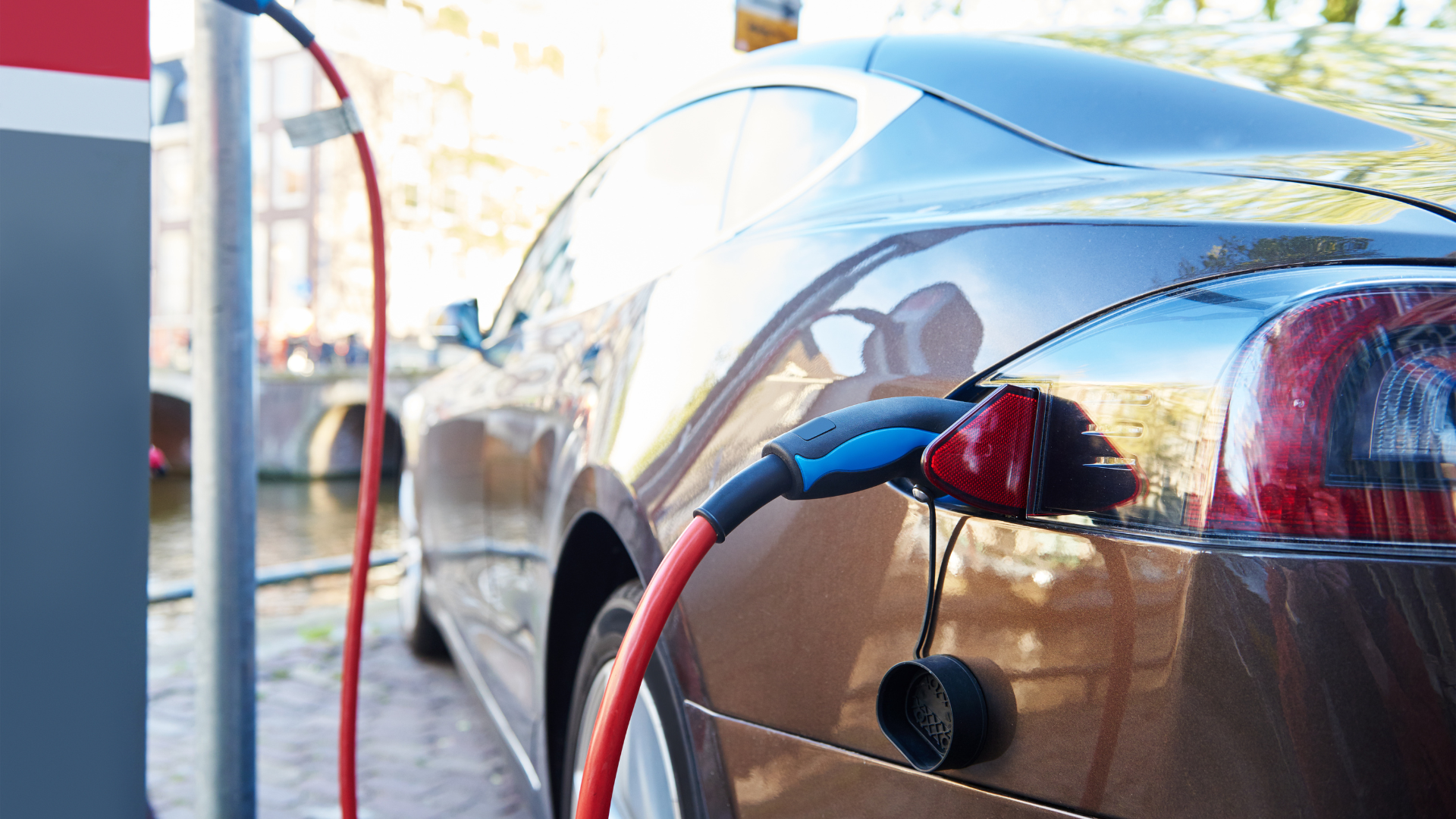 Electric car charging at a public charging station near a waterfront.