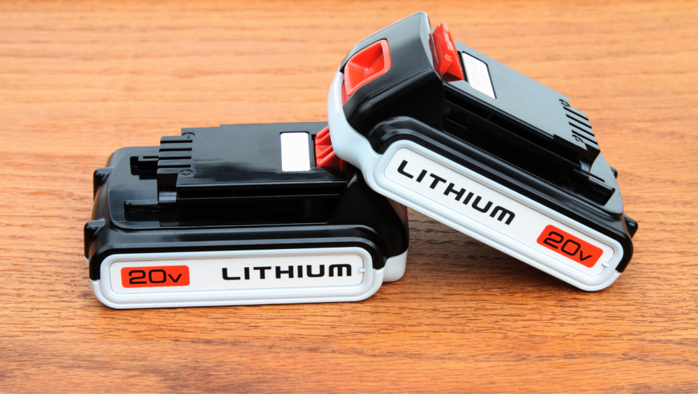 Two black and white 20V power tool Lithium-ion battery packs on a wooden surface.