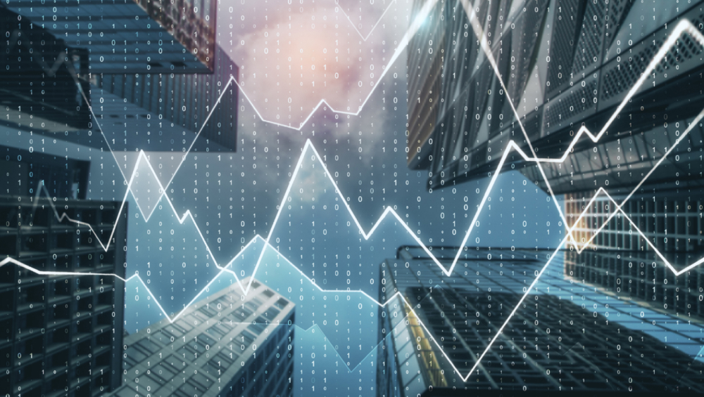 Worm's-eye view of skyscrapers and blue sky overlaid with a bright white stock market line chart and streaming binary code.