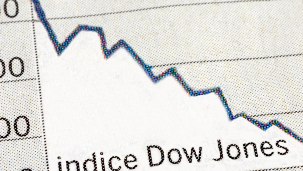 Close-up of a printed paper chart showing a sharp, jagged downward trend line labeled "indice Dow Jones" at the bottom right.