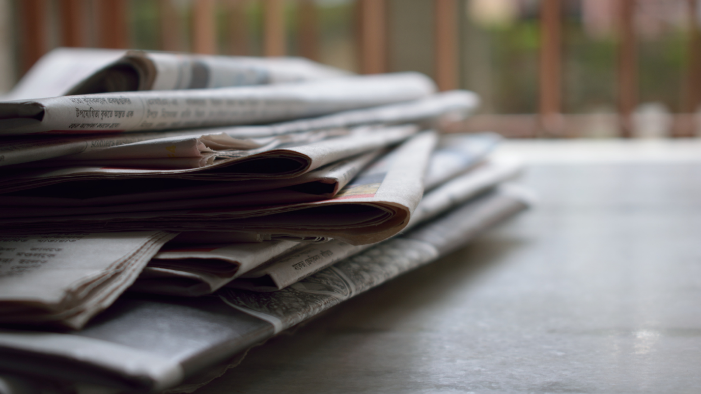 A wooden spoon held by a hand and filled with raw green lentils or pulses.