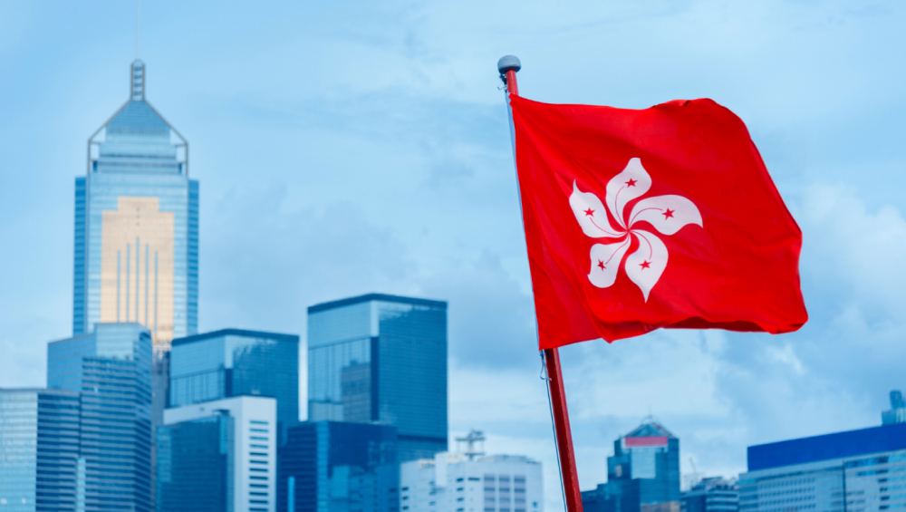 Hong Kong flag waving in front of modern skyscrapers in the city’s central business district.