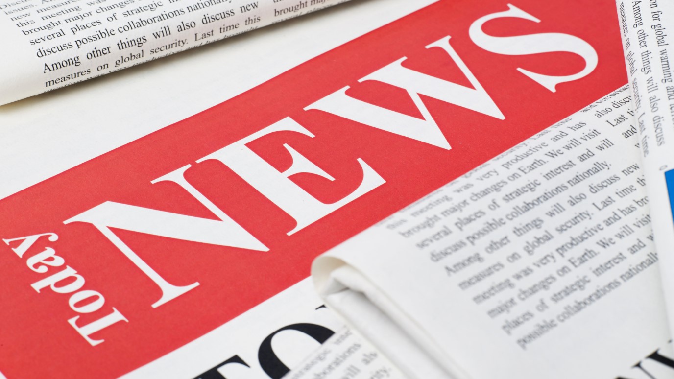 Close-up of a newspaper masthead with the word "NEWS" printed in large white capital letters on a striking red background.