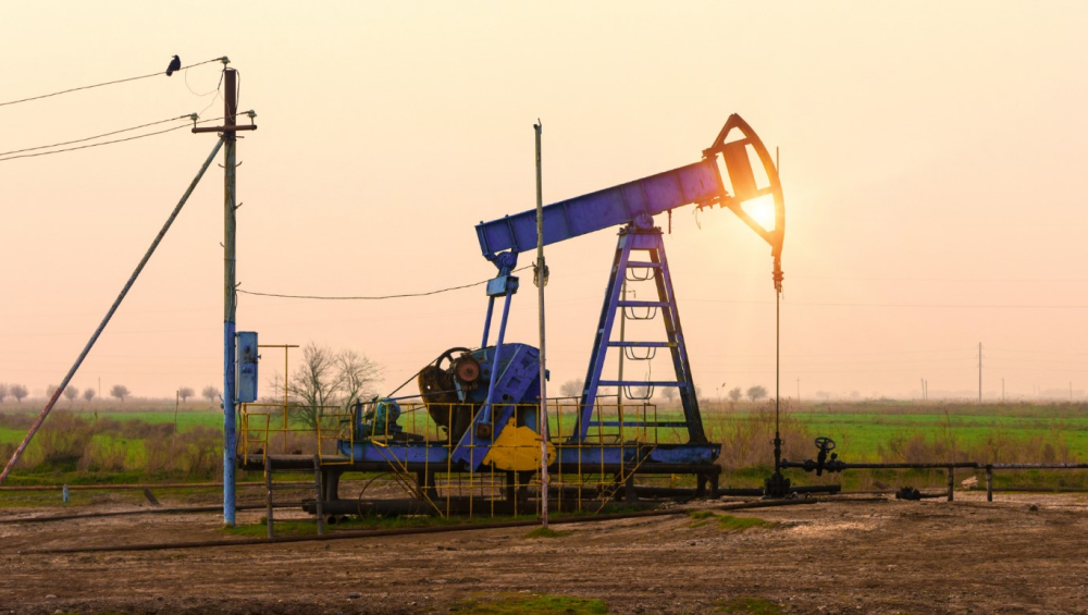 Oil pumpjack operating in a field during sunset.