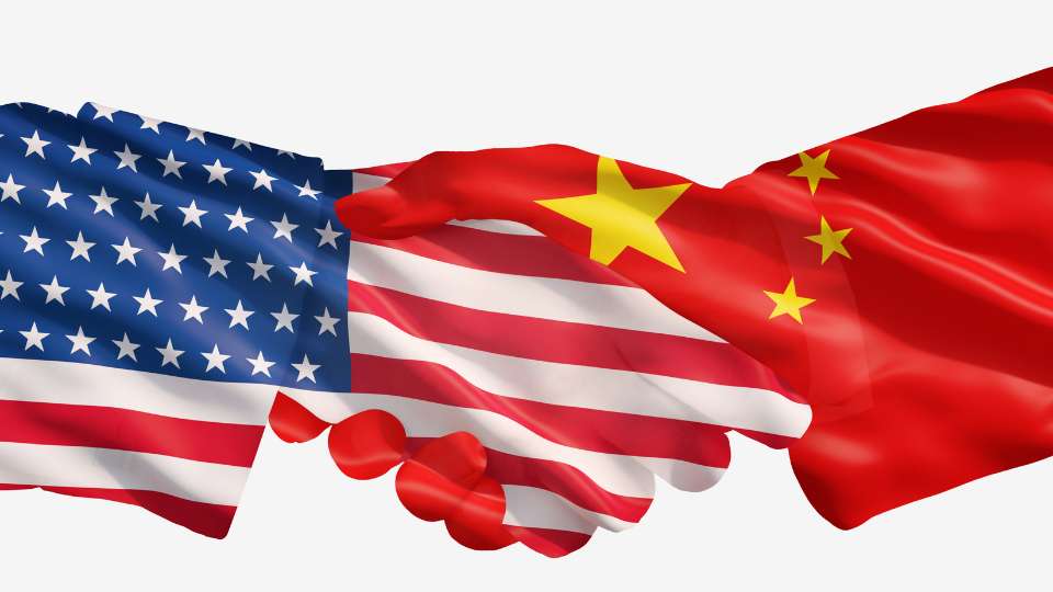 A digital illustration of two hands shaking, one painted with the US flag and the other with the Chinese flag, on a white background.