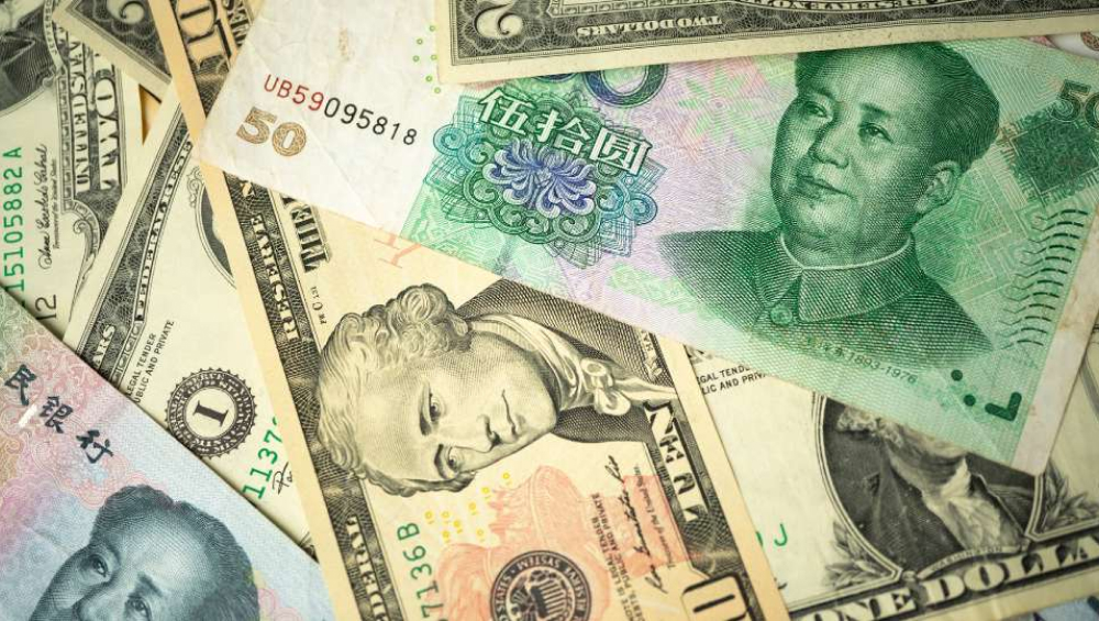 Mixed US dollar and Chinese yuan banknotes spread out, highlighting major global currencies.