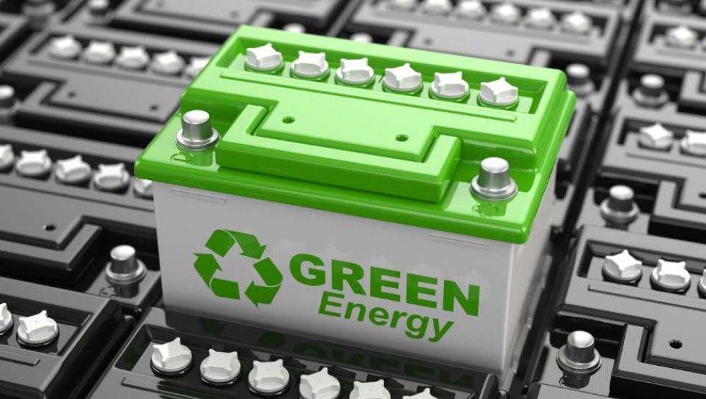 car battery with a bright green top and the text "GREEN Energy" and a recycling symbol on the side, surrounded by other dark batteries.