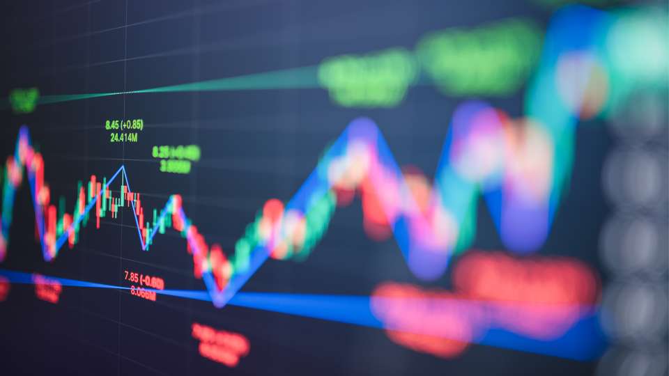 Blurred multicolor candlestick and line chart representing market volatility.