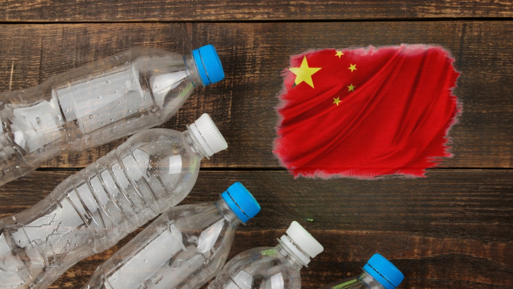 Clear plastic bottles with blue and white caps scattered on a wooden surface next to a painted, stylized Chinese flag.