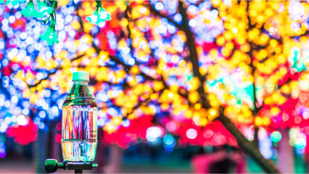 A clear plastic water bottle in the foreground, illuminated by a highly blurred background of vibrant, multi-colored bokeh lights