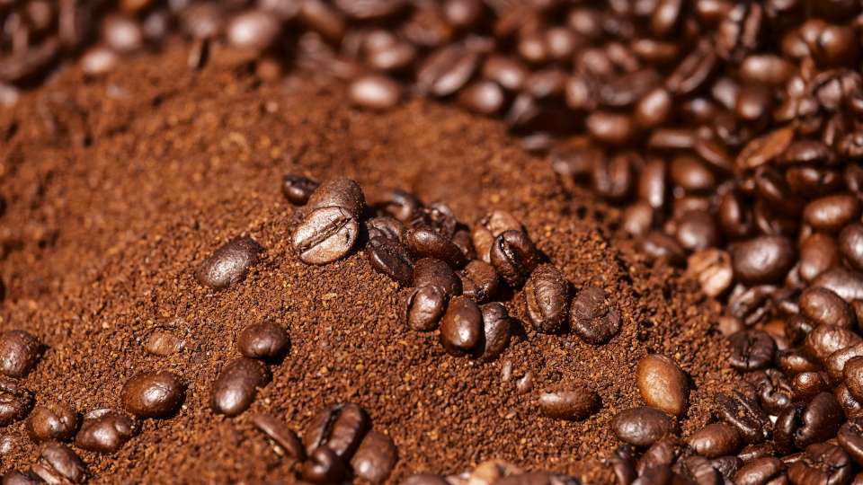 Ground coffee with whole roasted beans scattered on top.