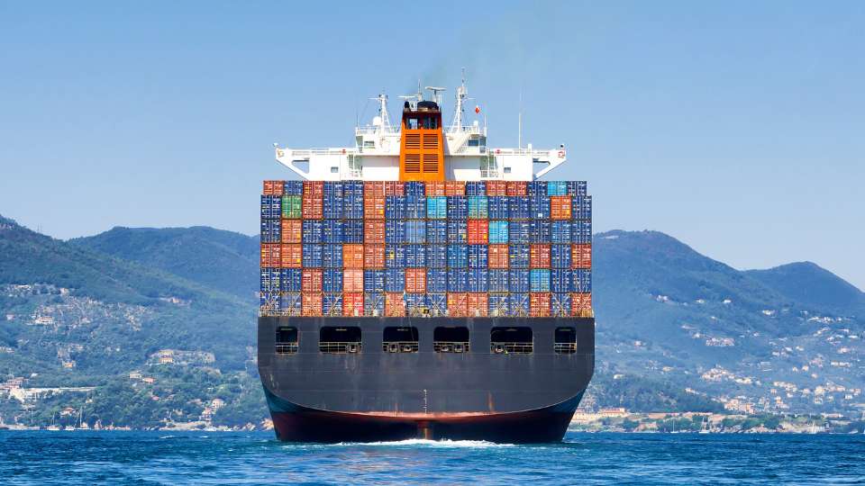 Container ship fully loaded with colorful containers at sea.
