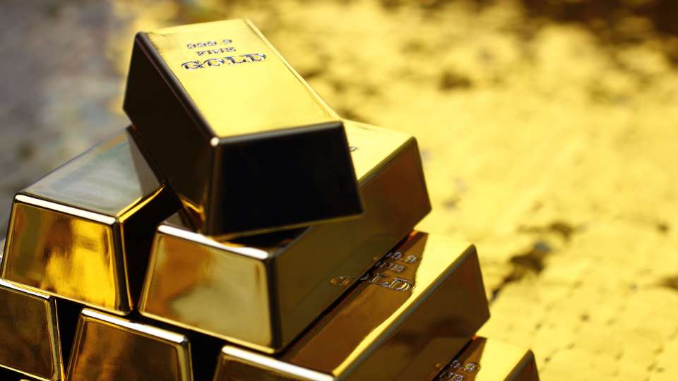 tacked pyramid of high-purity gold bars in a warm, gold-toned light.