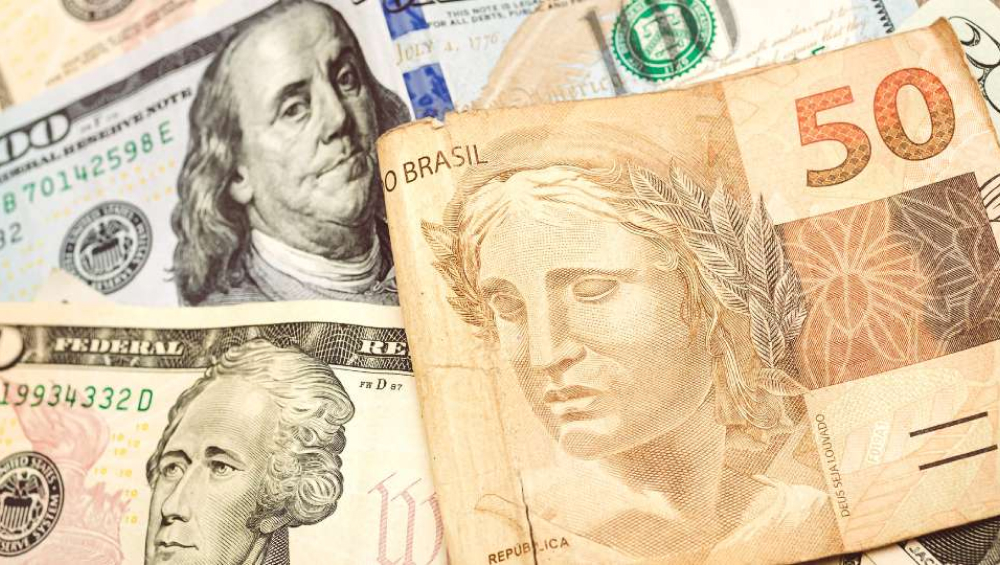 Close-up of a Brazilian 50 Real bank note overlapping US Dollar bills ($100 and $1), symbolizing the exchange rate.