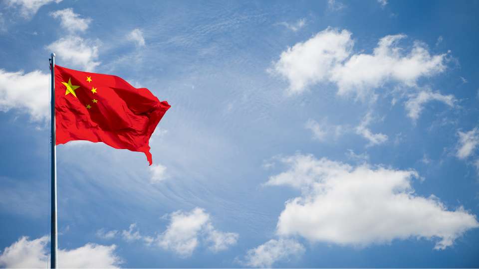Chinese national flag waving against a bright sky.
