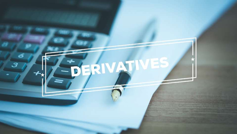 A pen, a calculator, and stacks of paper with the word “Derivatives” flashing on the screen.