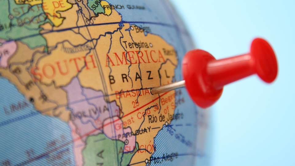 Pin stuck into a globe marking the country of Brazil in South America.
