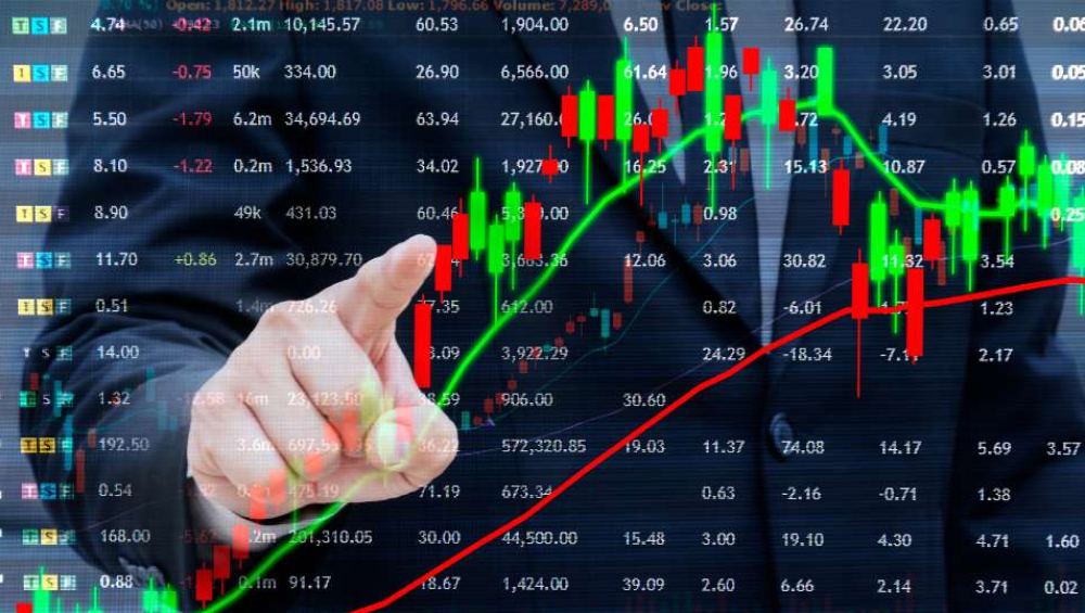 Business person pointing at a digital screen displaying stock market data, candlestick charts, and trend lines.
