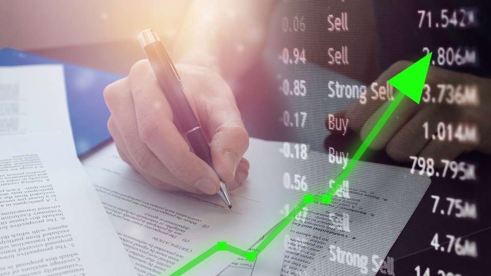 Hand signing a document with an overlay of a green upward-trending arrow and live financial data.