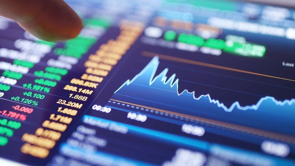 Finger touching a digital screen displaying stock market graphs, live quotes, and trading statistics.