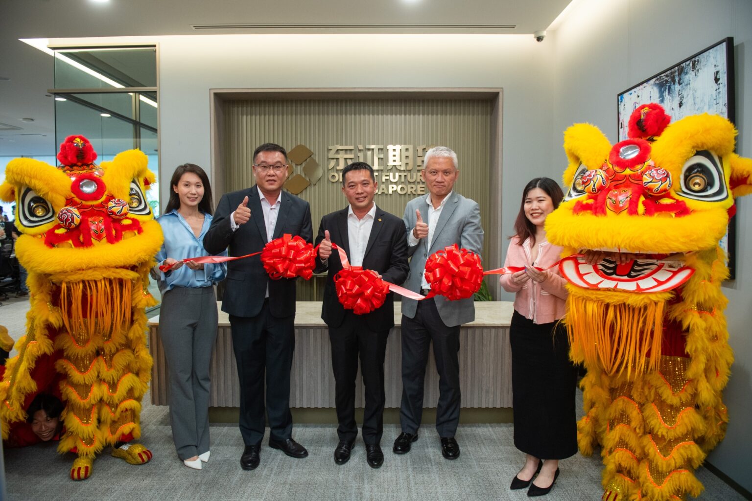 Orient Futures Singapore leadership team posing with lion dance performers at new office opening ceremony
