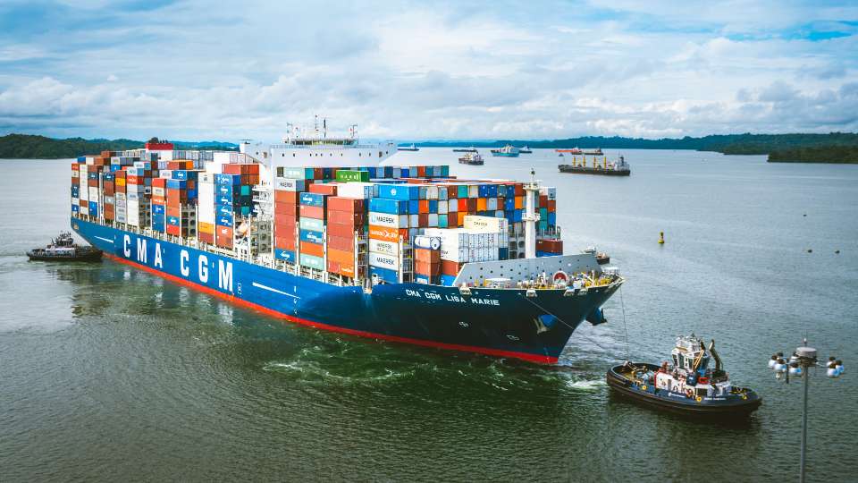 Cargo ship sailing on open sea with other vessels in the distance.