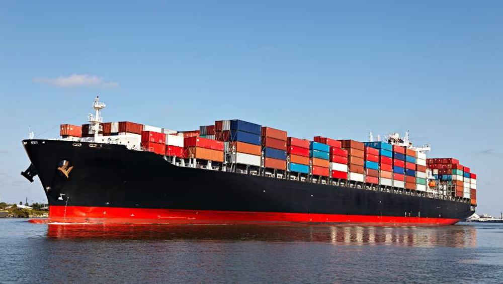 Large cargo ship loaded with colorful shipping containers sailing on the ocean.
