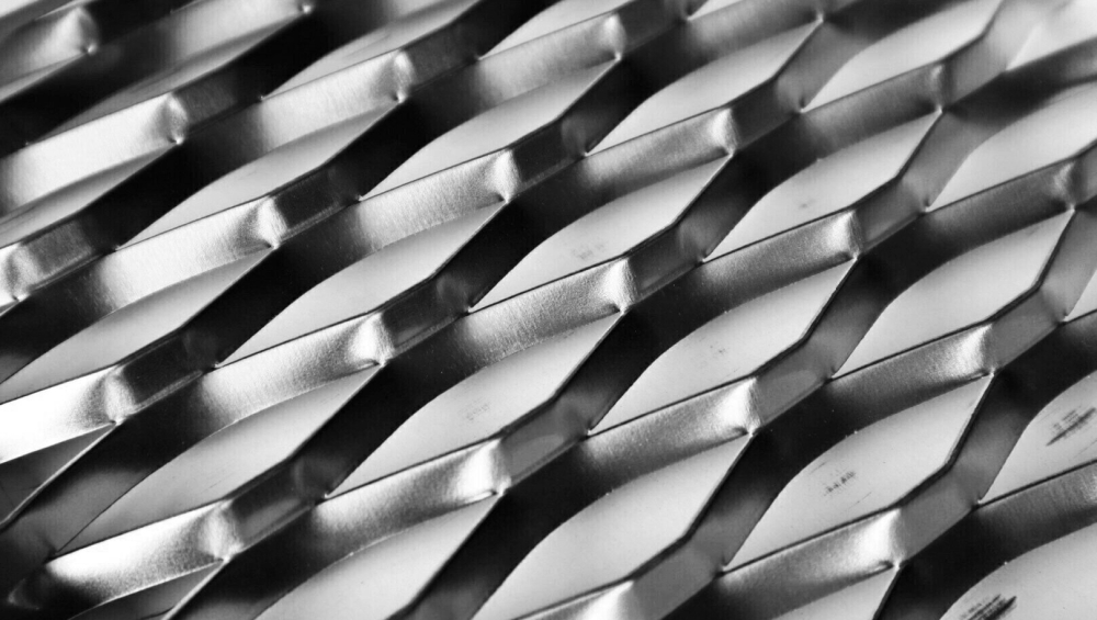 Close-up texture of shiny silver expanded metal mesh with a diamond pattern.