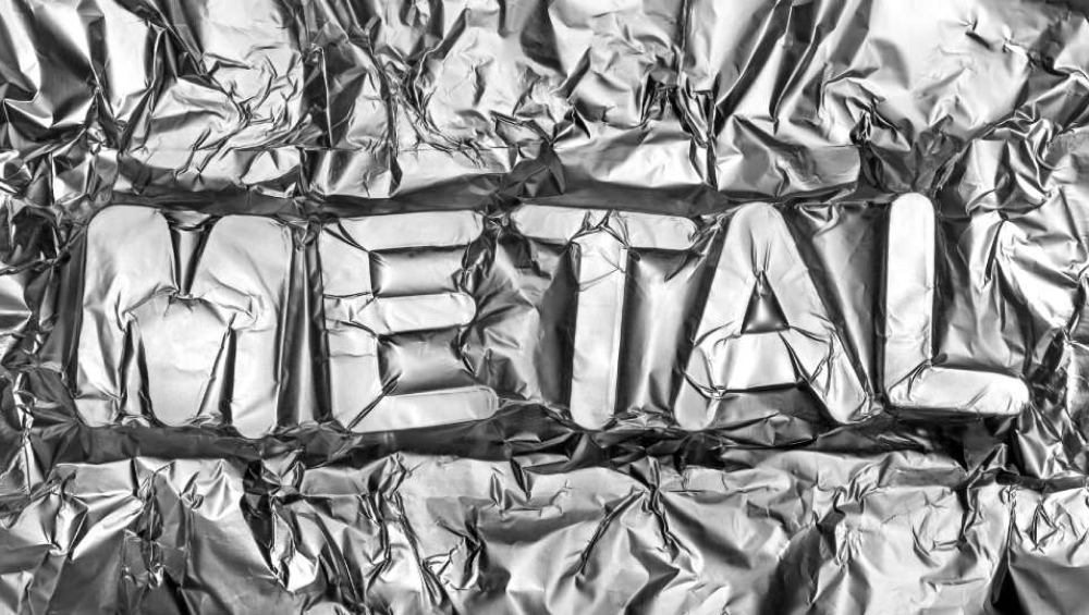 The word "METAL" embossed into a sheet of crumpled silver aluminum foil.