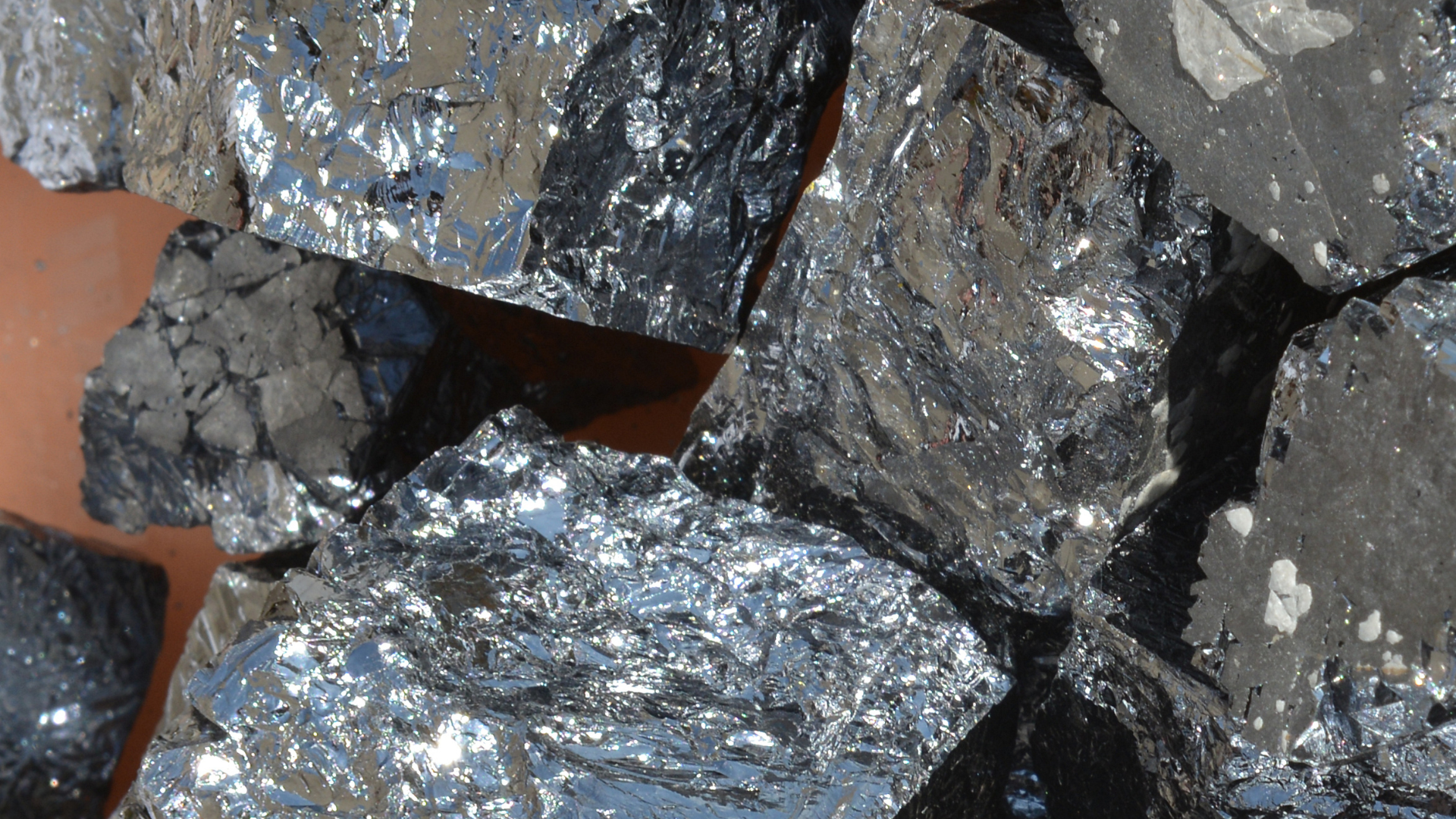 Close-up of large, jagged chunks of reflective black metallurgical coke or shiny coal.