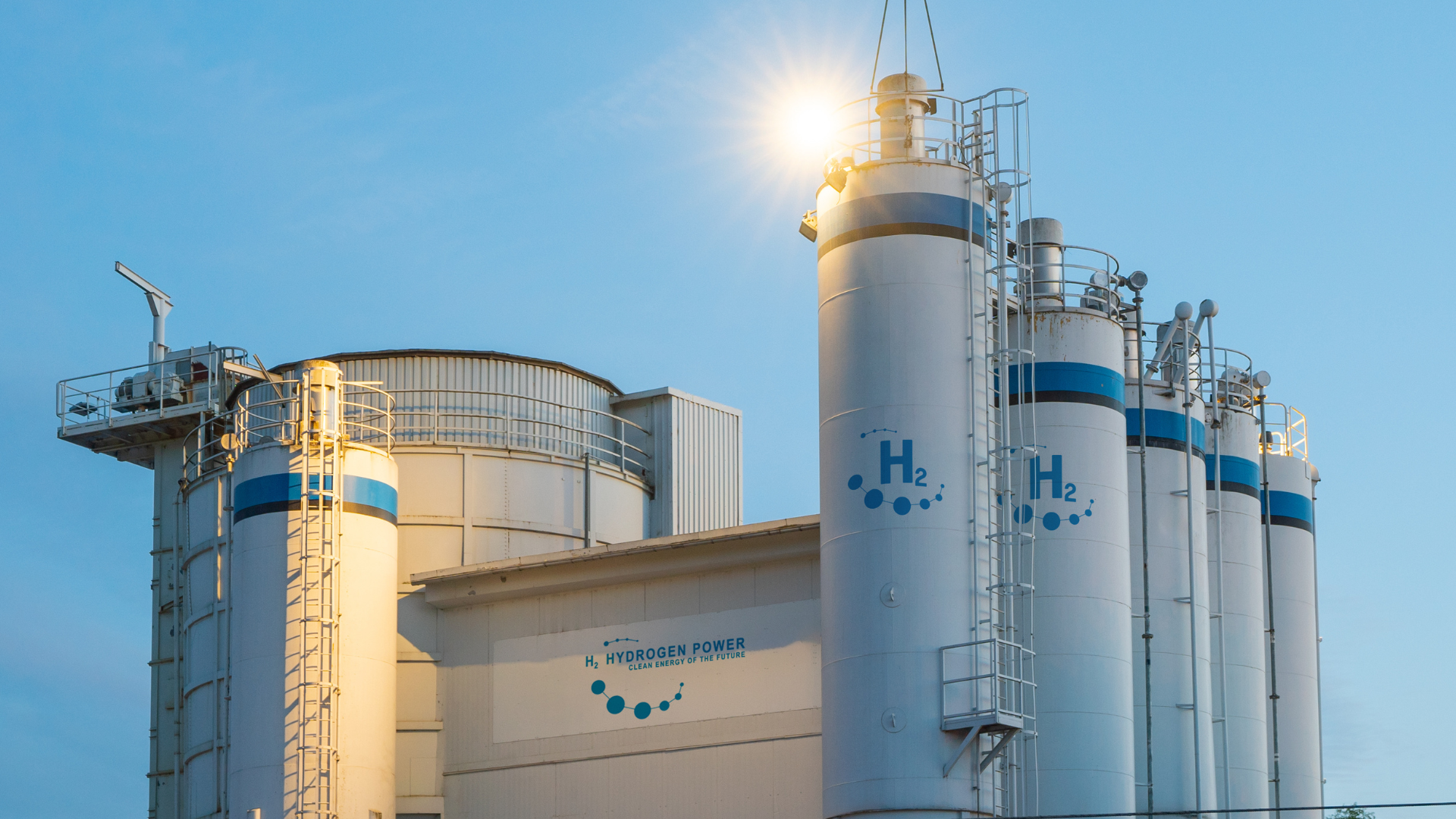 Industrial storage tanks marked with "H₂" and "Hydrogen Power" under a bright sun flare