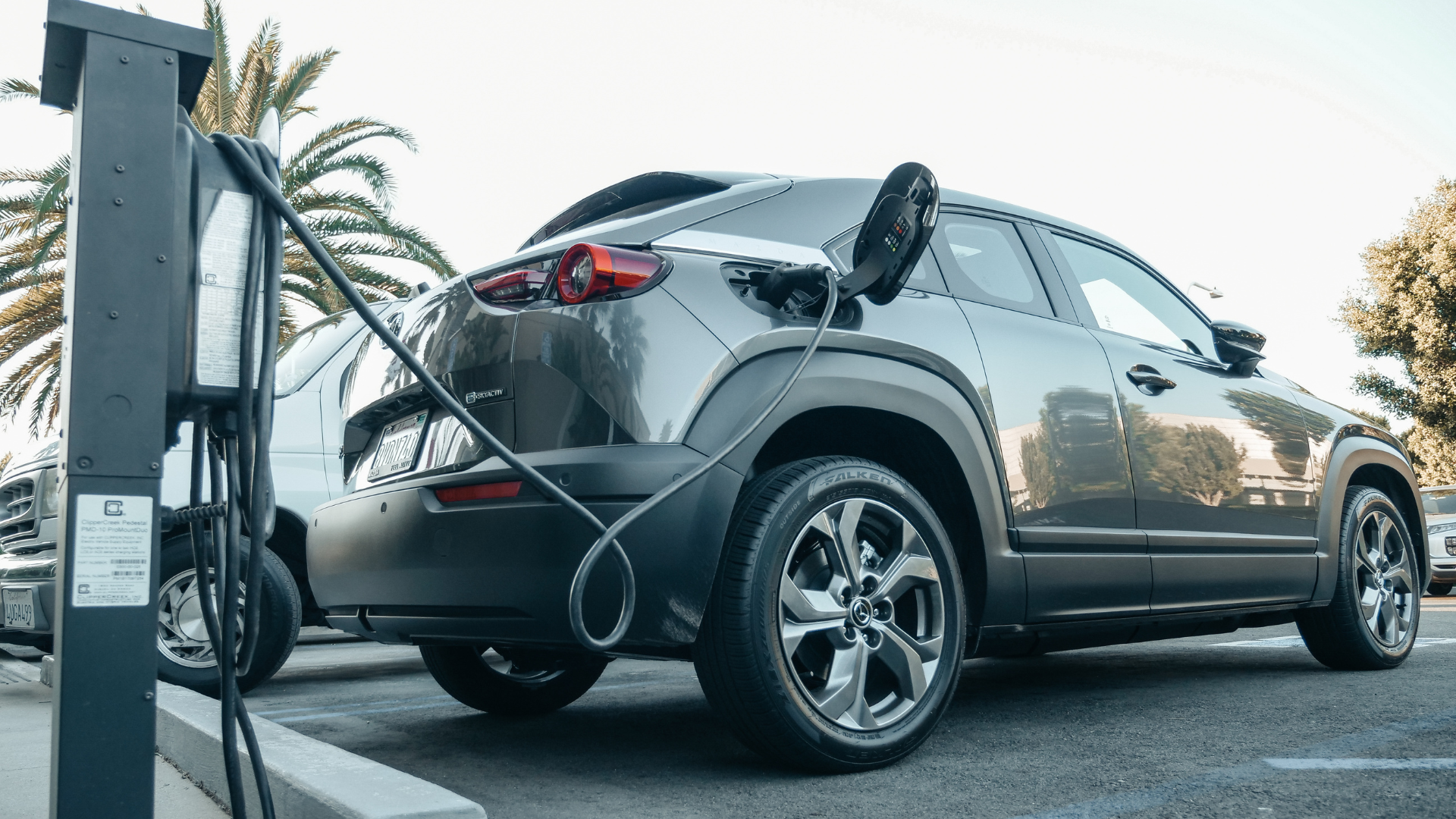Electric car charging at a public EV station in a parking lot.
