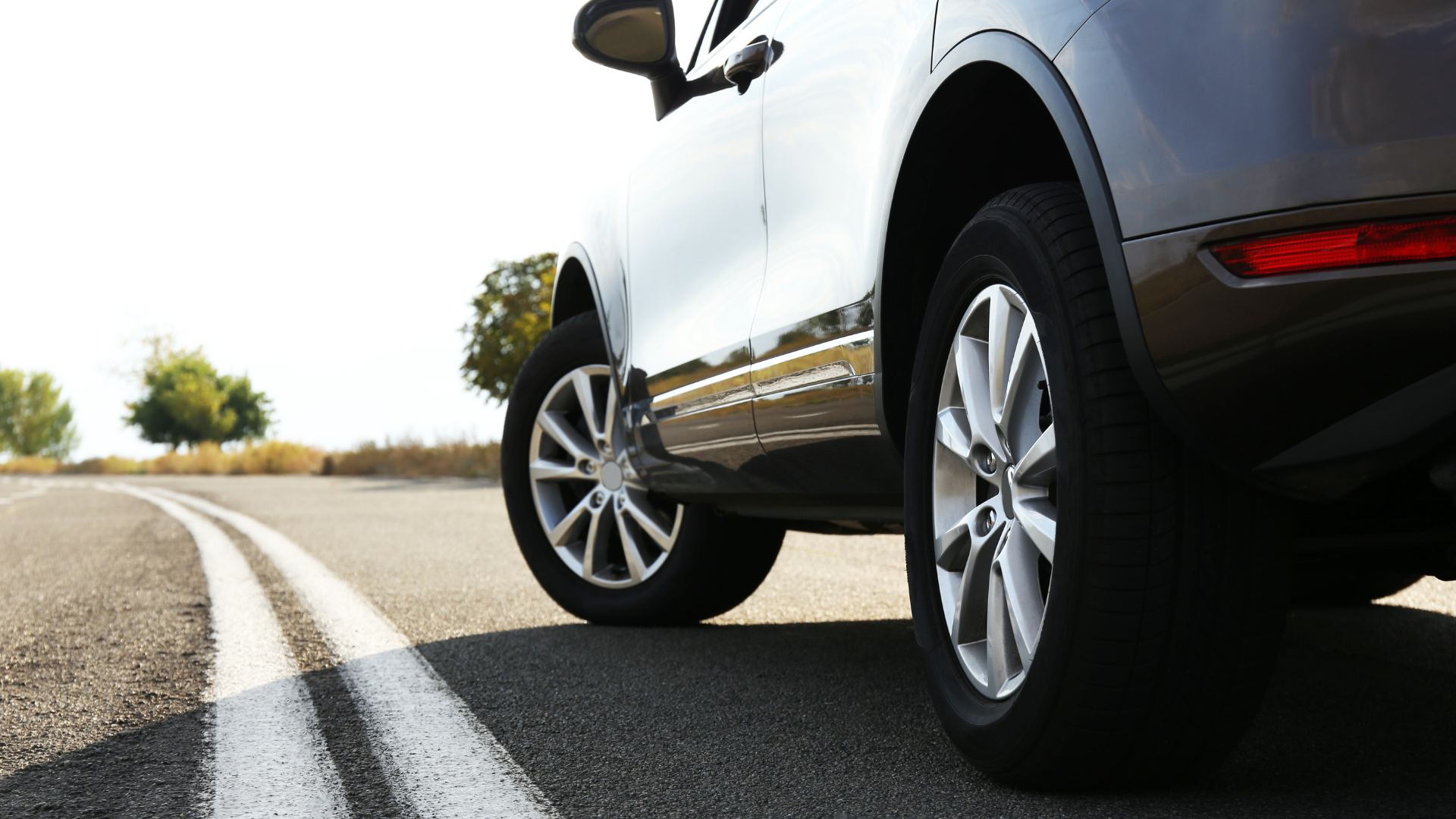 Close-up of a car driving on an open road under clear skies.