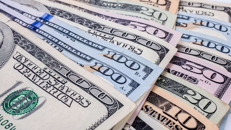 Close-up of a Brazilian 50 Real bank note overlapping US Dollar bills ($100 and $1), symbolizing the exchange rate.