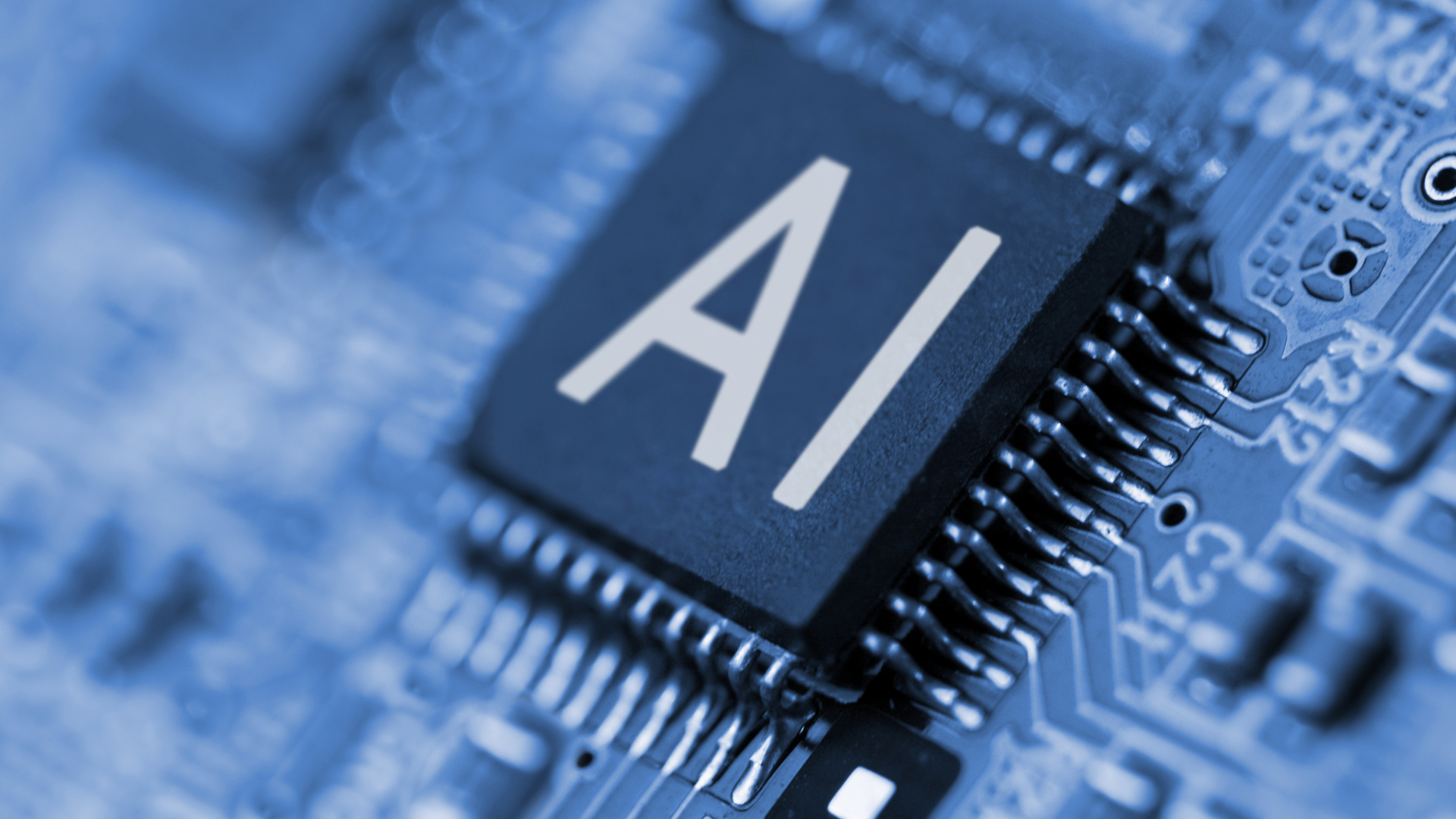Close-up of a computer chip labeled “AI” on a blue circuit board.
