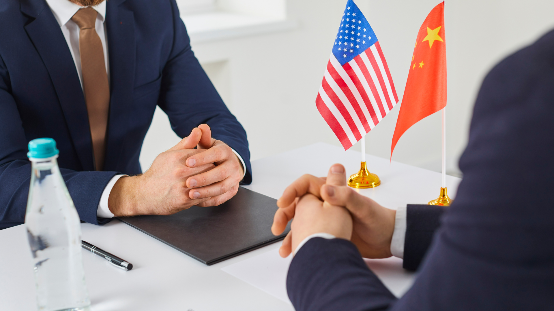 Business meeting between U.S. and China representatives with national flags on table.