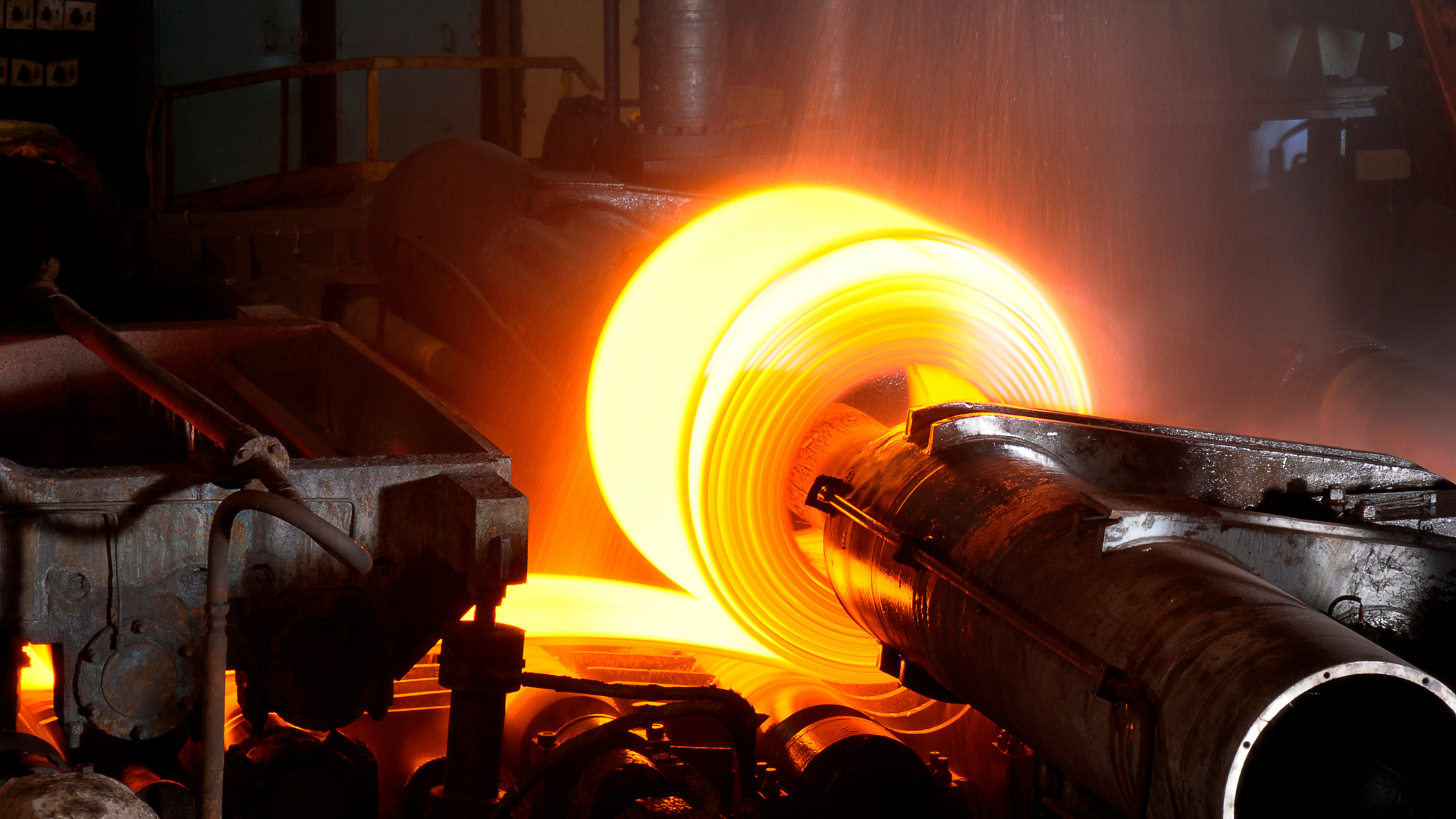 Hot steel coil being processed and rolled in an industrial steel mill.