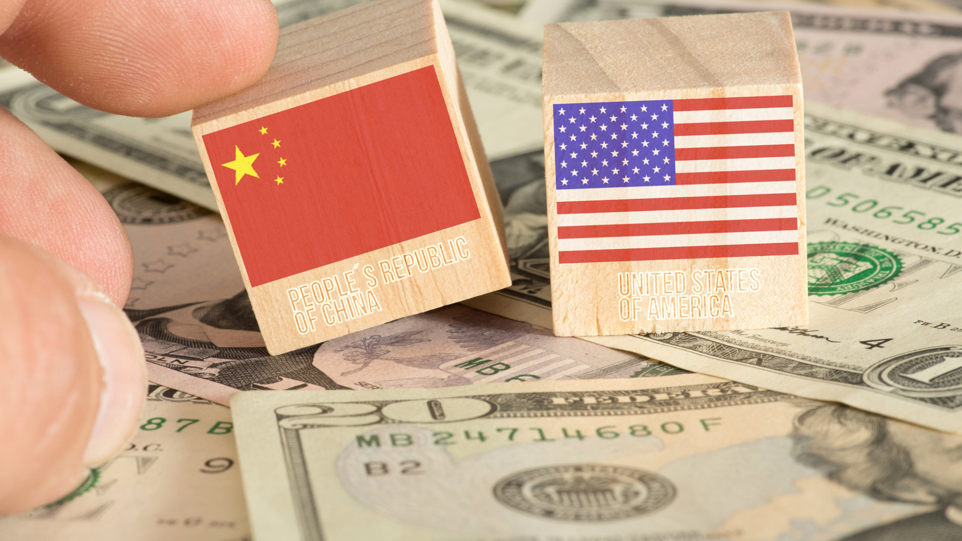 Wooden blocks with China and U.S. flags placed on U.S. dollar bills.