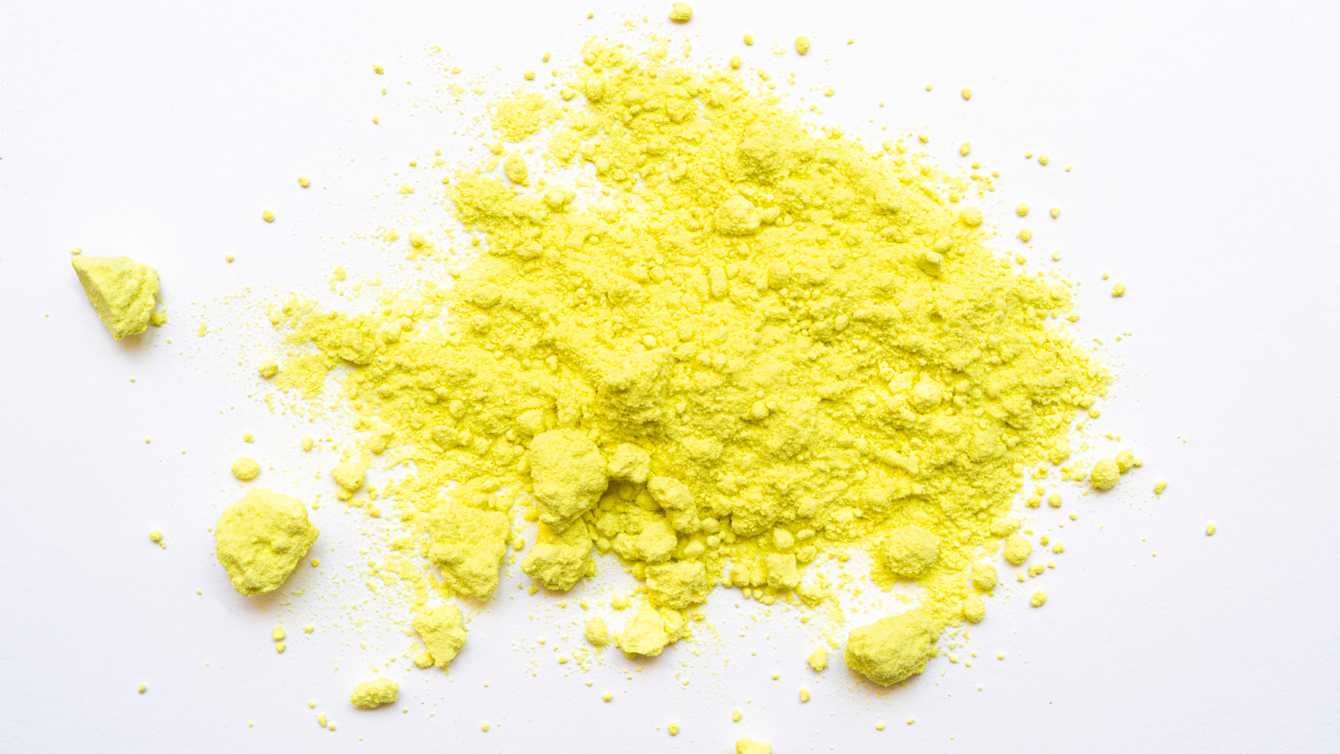 Bright yellow powder scattered on a white background.
