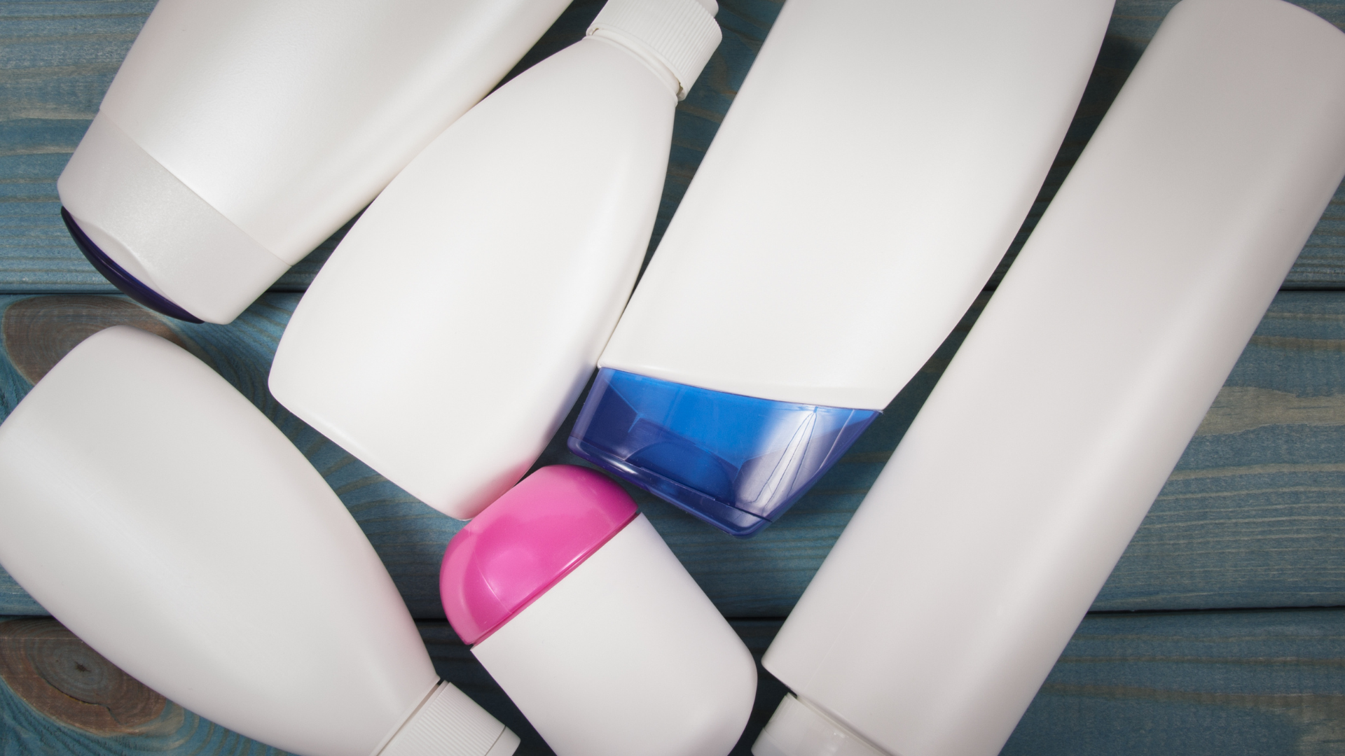 Assorted white plastic cosmetic bottles and containers on a wooden surface.
