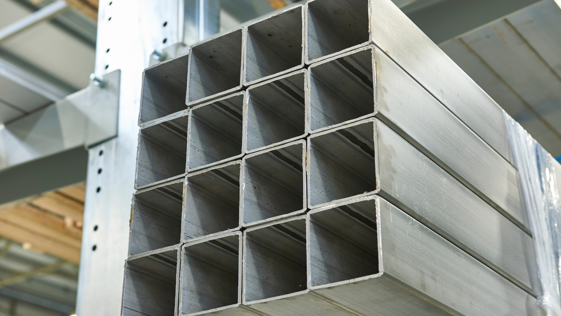Stack of stainless steel rectangular tubes stored in an industrial warehouse.