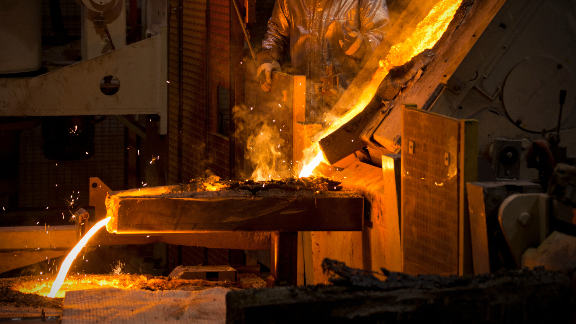 Worker pouring molten metal in a foundry during the smelting process.