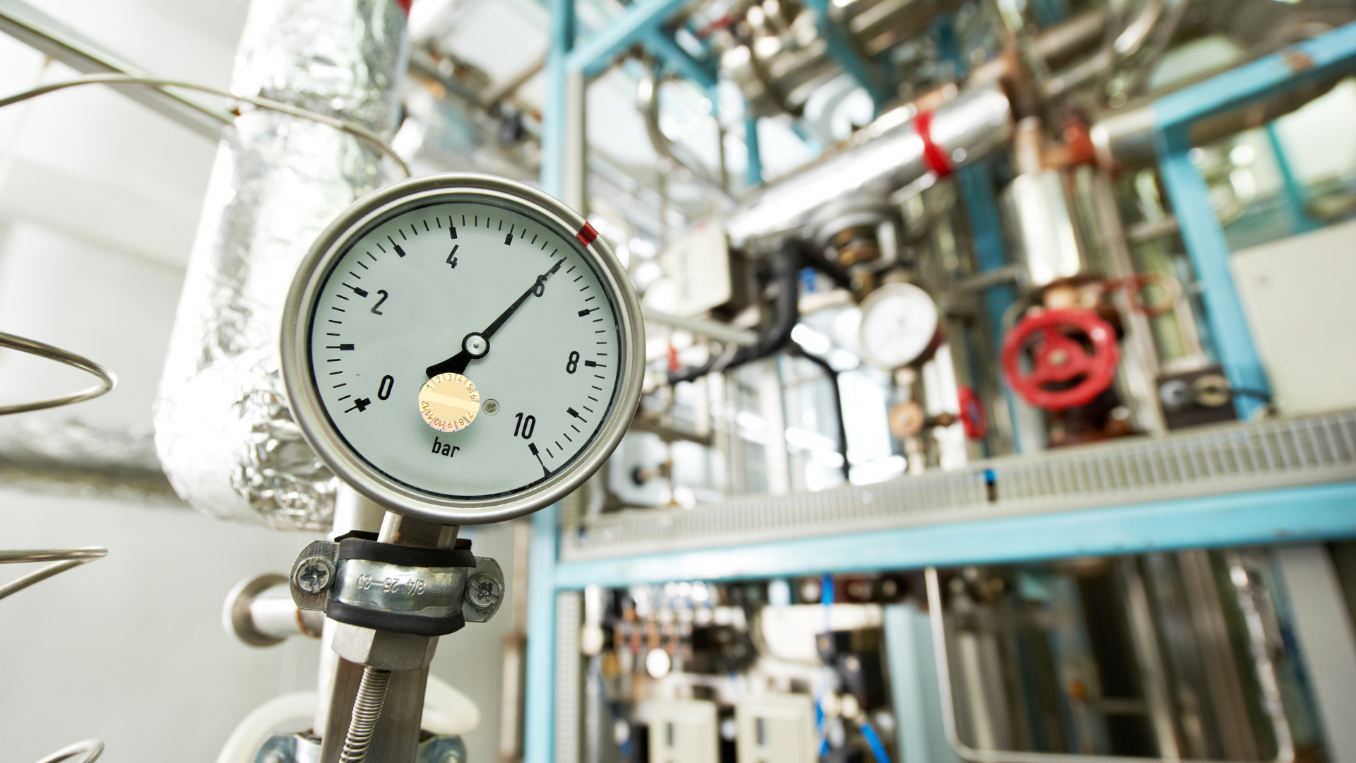 Industrial pressure gauge showing 6 bar in a modern factory setting.