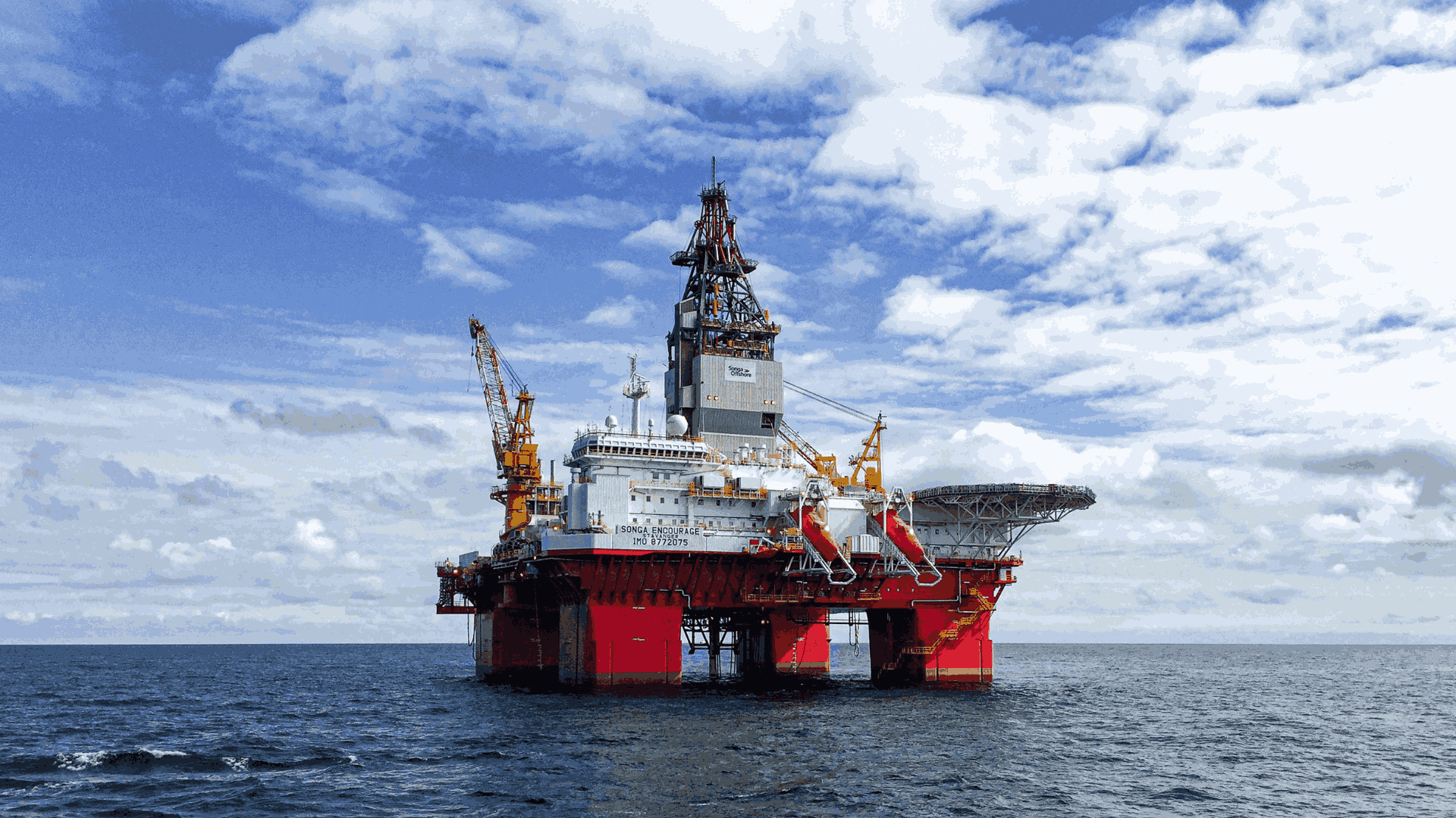Offshore oil drilling platform in open ocean under blue sky.