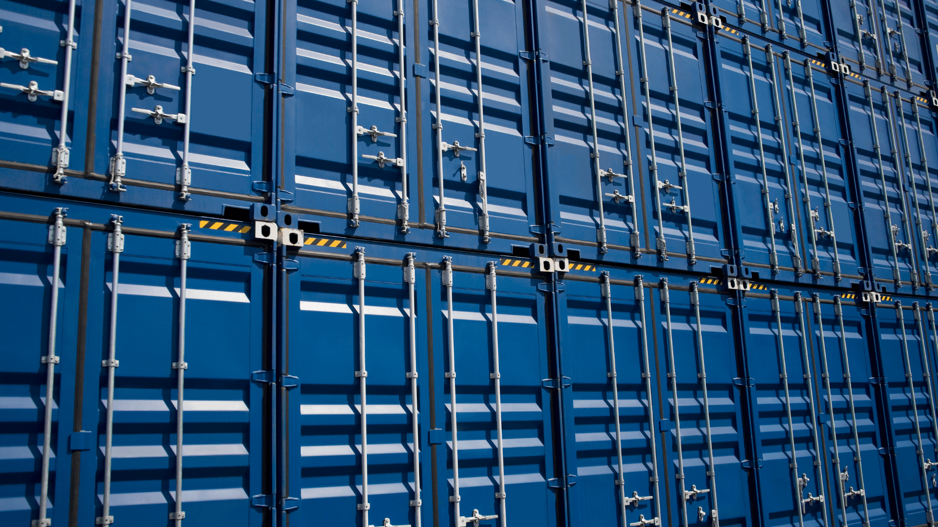 Stacked blue shipping containers in a storage yard.
