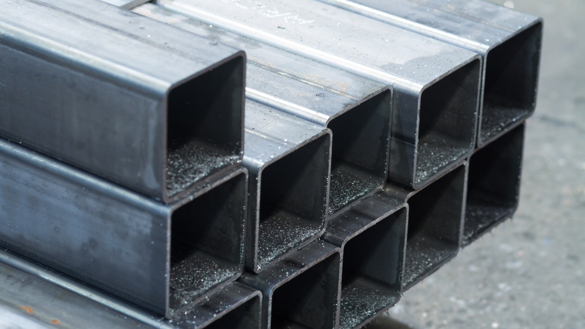 Close-up of stacked rectangular steel pipes with smooth surfaces.