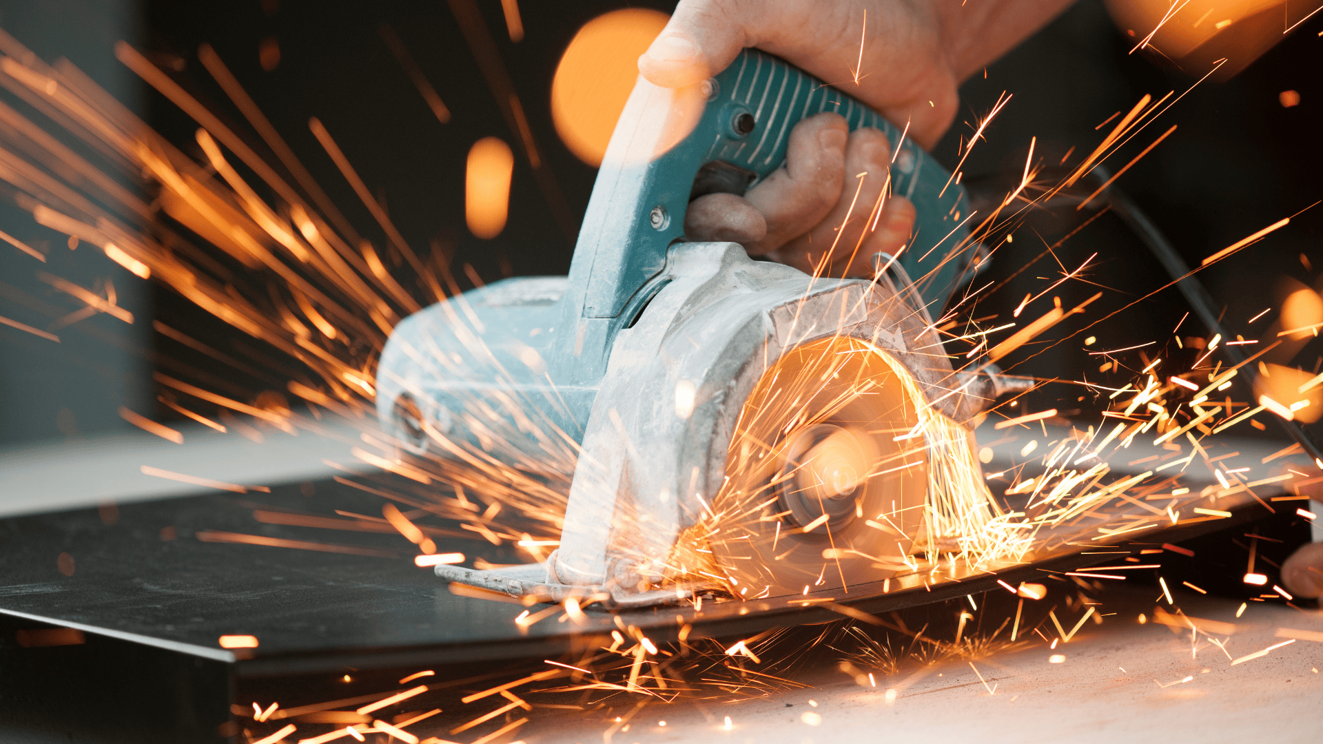 Hand holding a circular saw cutting through metal, sparks flying.