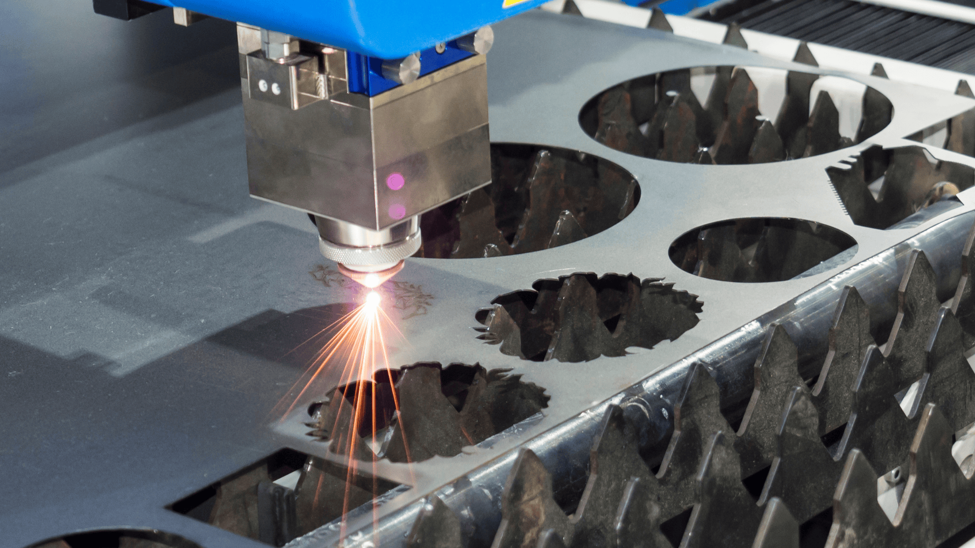 High-precision laser cutting machine processing metal sheet with bright sparks.